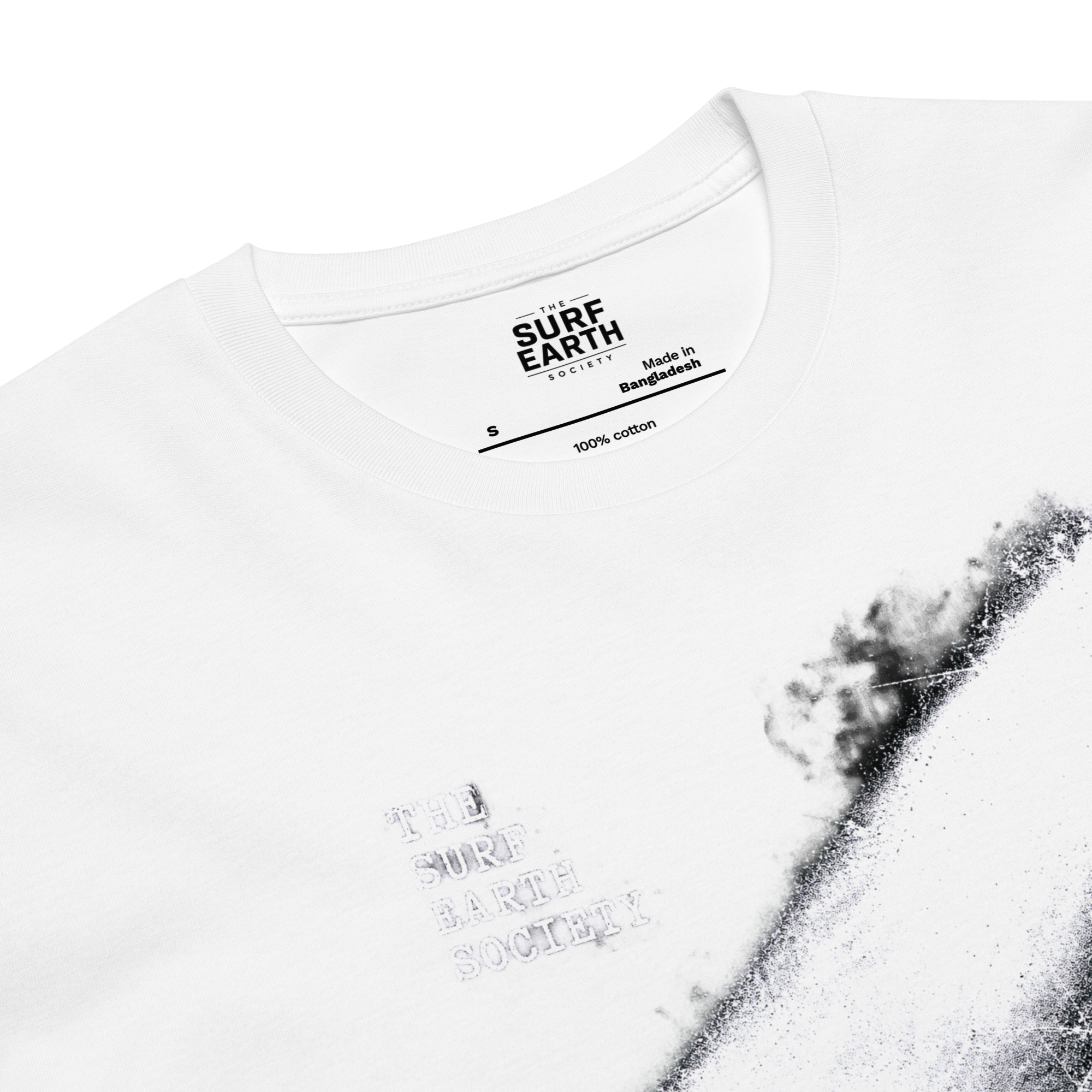 Close-up of a white short-sleeve t-shirt by Surf Earth Bangladesh, featuring a black powder-spray graphic on the right side and tonal gray text reading 'THE SURF EARTH SOCIETY' on the left chest.