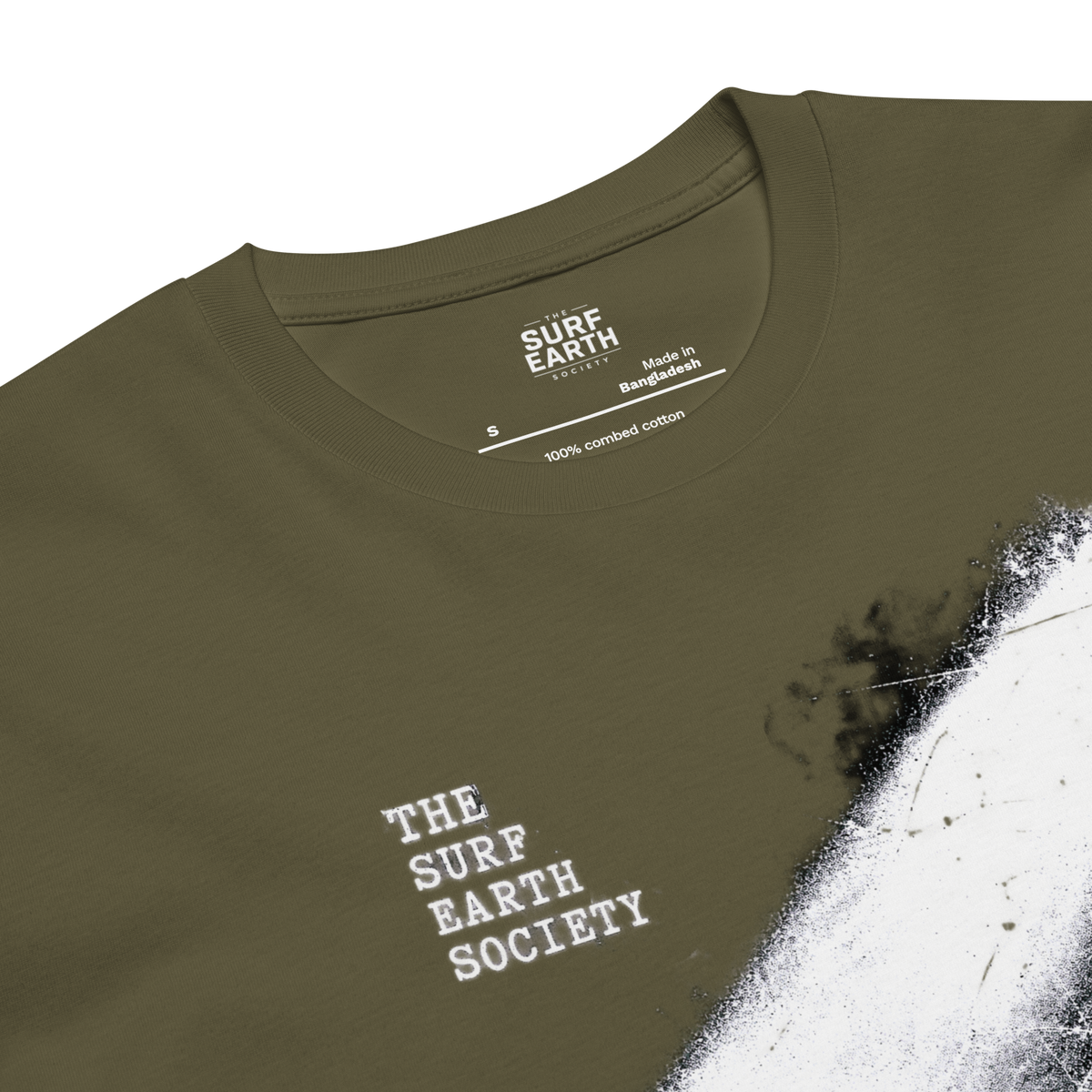 Close-up of an olive green t-shirt with a white paint-splatter graphic and white distressed text reading 'THE SURF EARTH SOCIETY' on the chest. The inside collar shows 'SURF EARTH SOCIETY' branding.