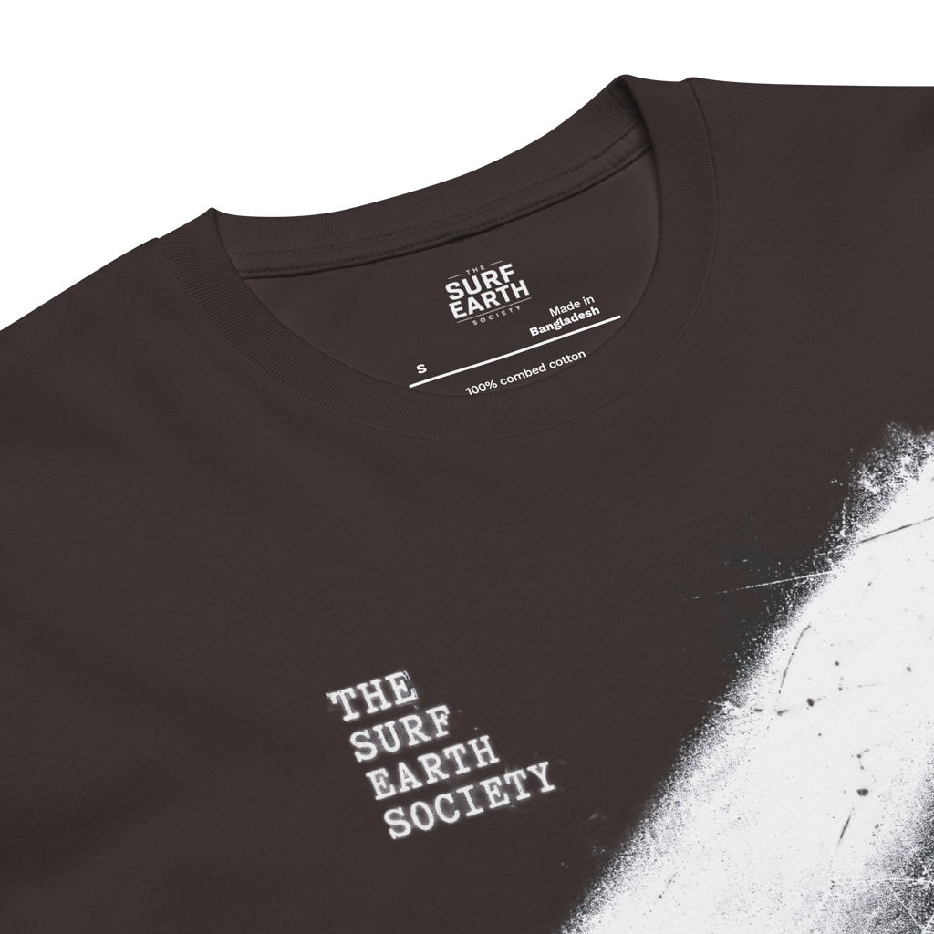 Closeup coal color cotton Vintage surf T-shirt featuring a longboard surfer entering the ocean under a dramatic 